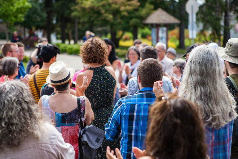 A neighborhood event gathering and community members are clapping